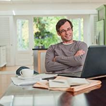 Man smiling at his computer while sitting at a table